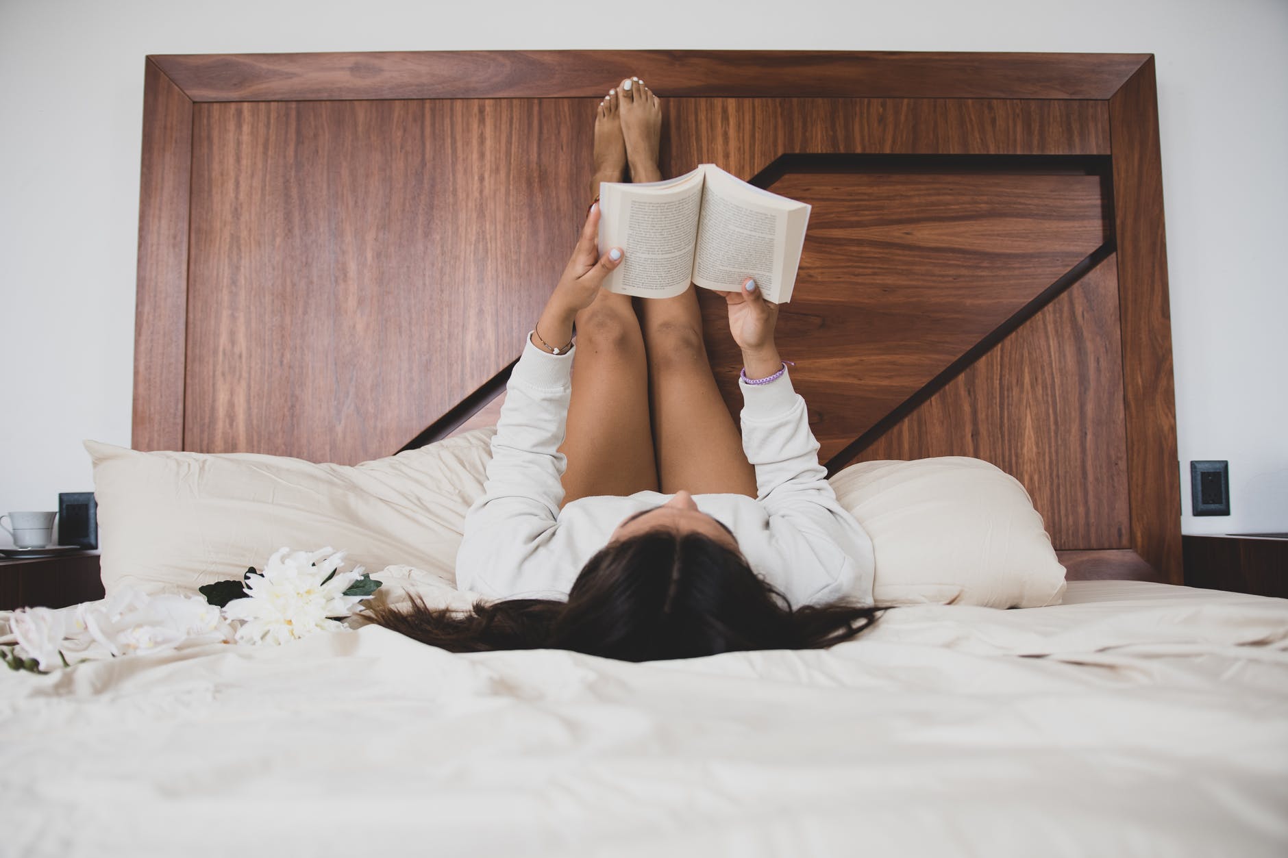 a woman reading a book while lying in bed